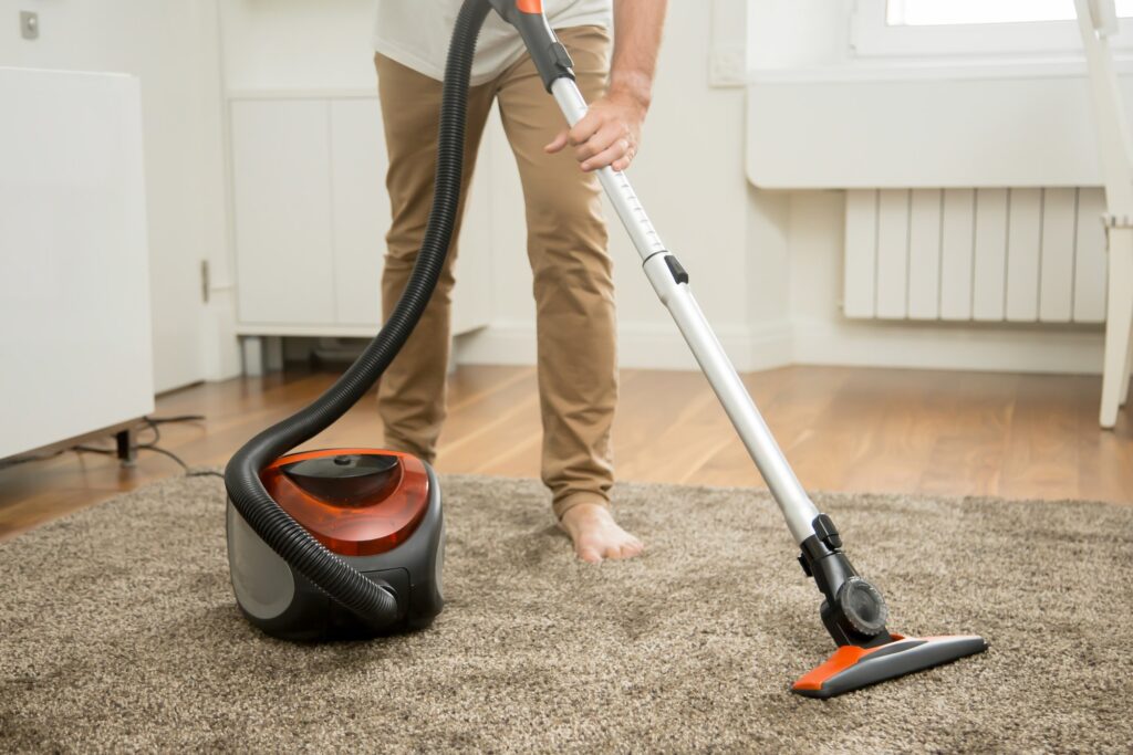 Close up of man vacuum cleaning the carpet